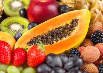 Fresh raw organic summer berries and exotic fruits. Macro. Close up. Pineapple, papaya, grapes, nectarine, orange, apricot, kiwi,  lychees, cherry and physalis, raspberry.