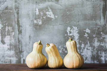 Yellow Halloween pumpkins in wooden tray on grey background