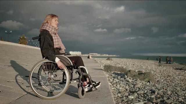 Lonely handicapped woman in wheelchair near the sea