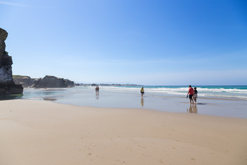Ribadeo, Spain. Tourists at low tide on the shore of the Atlantic Ocean
