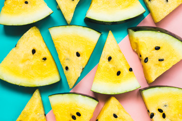 cut off triangular slices of ripe yellow watermelon on blue-pink background