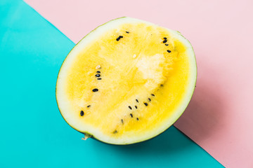 cut off triangular slices of ripe yellow watermelon on blue-pink background