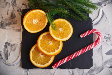 Fresh slised oranges and with candy and spruce branch on the gray background