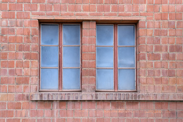 Two windows on a brick wall with blue glass panes