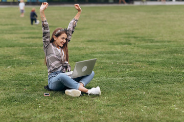 Fototapeta premium Woman sitting in park on the green grass with laptop.Student studying outdoors