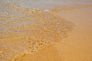 Fototapeta na wymiar Soft waves with foam of sea on the sandy beach