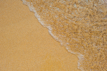 Soft waves with foam of sea on the sandy beach
