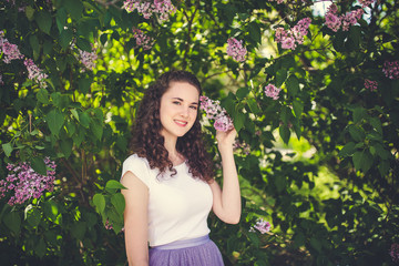 Cheerful young woman in a white t-shirt under the blooming trees.