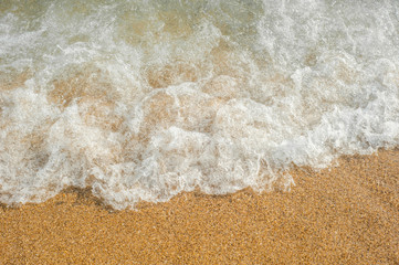 Soft waves with foam of sea on the sandy beach