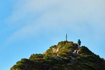 Fototapeta premium woman climbs to the top of a mountain with a backpack
