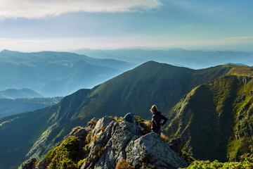 Fototapeta premium woman climbs to the top of a mountain with a backpack