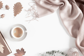 Autumn home cozy composition. Dried autumn leaves, cup of coffee, book, scarf, flowers on white...