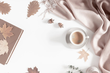 Obraz na płótnie Canvas Autumn home cozy composition. Dried autumn leaves, cup of coffee, book, scarf, flowers on white background. Fall background. Flat lay, top view, copy space