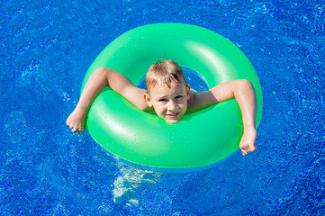 Happy kid boy having fun in an swimming pool. Active happy healthy preschool child learning to swim. With safe floaties or swimmies.