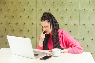 You are liar. Young freelancer woman with black dreadlocks hairstyle in pink blouse is sitting and...