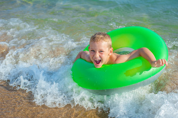 Happy boy swimming and playing at sea with rubber ring