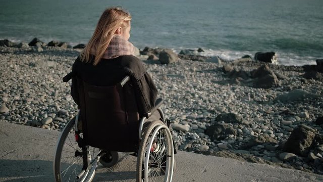 Disabled woman in wheelchair is alone with sea