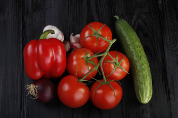 branch with tomatoes, cucumber, onion and garlic on wooden background. top view