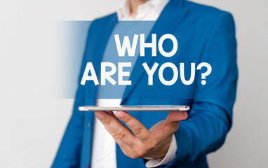 Handwriting text Who Are You Question. Conceptual photo asking about its identity or demonstratingal information Man in the blue suite and white shirt holds mobile phone in the hand