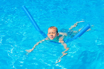Happy kid boy having fun in an swimming pool. Active happy healthy preschool child learning to swim. With safe floaties or swimmies.