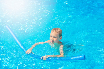 Boy at swimming pool class learning to swim.