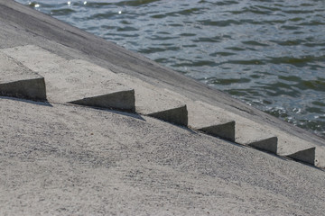 Fototapeta premium Concrete steps lead to the water in the park