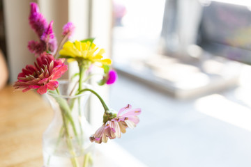 Fresh colorful wild flowers in glass vase on cafe table, close up, copy space