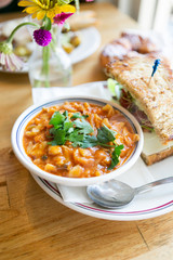 Close up of minestrone soup with california club sandwich on cafe table