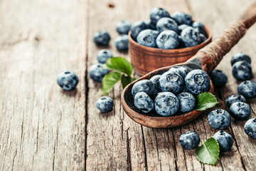 Blueberries in wooden spoon on old wood table. Healthy eating and nutrition concept.