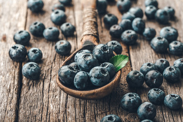 Blueberries in wooden spoon on old wood background. Healthy eating and nutrition concept.