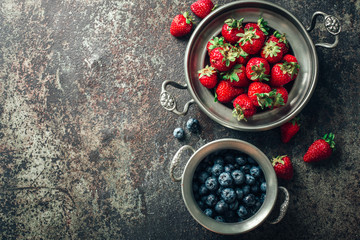 Freshly picked Strawberry in bowl on dark metal background. Healthy eating and nutrition.