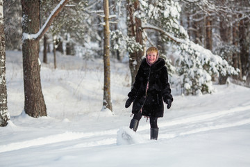 Fototapeta na wymiar Young woman at winter in the snowy forest.
