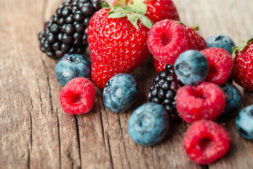 Fresh Summer Berries mix with Strawberry, Raspberry, Red currant, Blueberry and Blackberry on wood background.