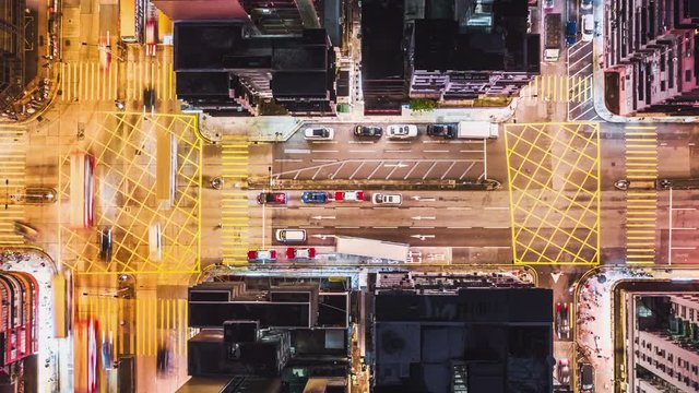 4K UHD Time-lapse of car traffic on road and people crossing street at night in Hong Kong downtown district, drone aerial top view. Commuter, Asia city life, or public transportation concept, Panning