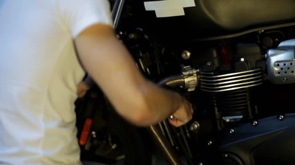 man repairing his motorcycle in the garage.