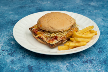 Hamburger with meat, tomato, lettuce and french fries.