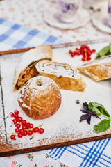 Apple strudel and apple on a board sprinkled with powdered sugar