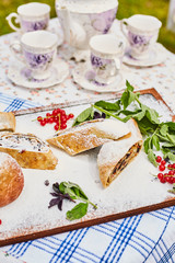 Apple strudel and apple on a board sprinkled with powdered sugar