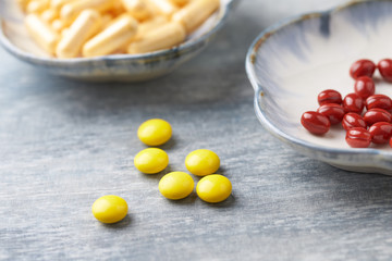 Vitamin C, Beta-Carotene tablets and Coenzyme Q10 capsules. Antioxidants. Concept for a healthy dietary supplementation. Bright wooden background. Close up. Copy space.  