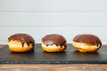 Donut with white glaze and chocolate crumbs, donut with chocolate glaze on light wooden table