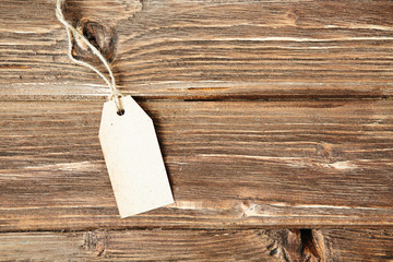 Blank tag on wooden background One paper blank tags with rope on wooden background.
