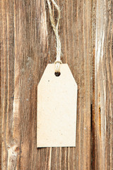 Blank label on wooden background One paper blank tags with rope on wooden background.