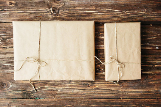 Two gift boxes wrapped in kraft paper on wooden table