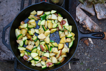 Cooking over campfire cast iron skillet veggies