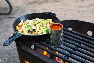 Cooking dinner over campfire on cast iron skillet