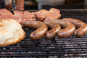 The cook fries sausages on a charcoal grill. Food and cooking equipment at a street food festival