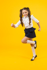Fototapeta na wymiar Being in a hurry. Active small child in formal wear rushing to school on yellow background. Happy girl leading active lifestyle. Little schoolchild looking active and alive. Active and energetic