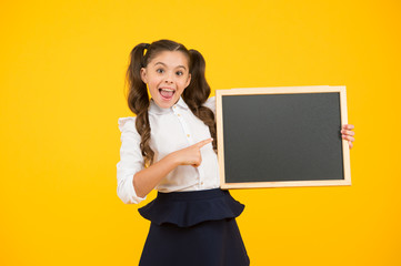 Schoolgirl pupil long hair informing you. School girl hold blank chalkboard copy space. Announcement and promotion. Check this out. Girl school uniform hold blackboard. Back to school concept