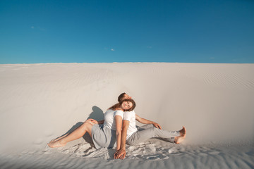 Fototapeta na wymiar Romantic pair sit on white sand and huggins, in desert