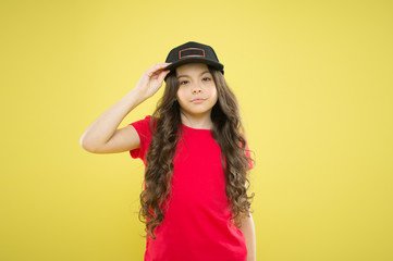 All girls are gorgeous. kid fashion. happy girl in trendy hipster cap. hipster child on yellow backdrop. happy childhood. beauty and fashion. small girl with long hair. cool girl with long curly hair